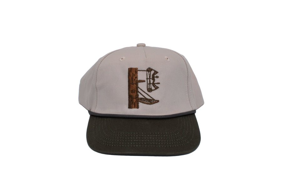 A lock on stand with a bow on a cream hat with a green bill. The letters DF are carved into the tree