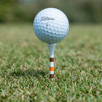 Golf ball teed up on a brown and orange striped Delta Feather golf tee