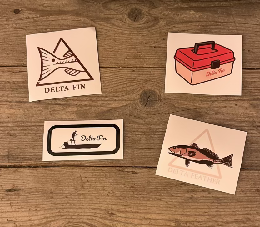 Four Delta Fin branded stickers on a wooden surface