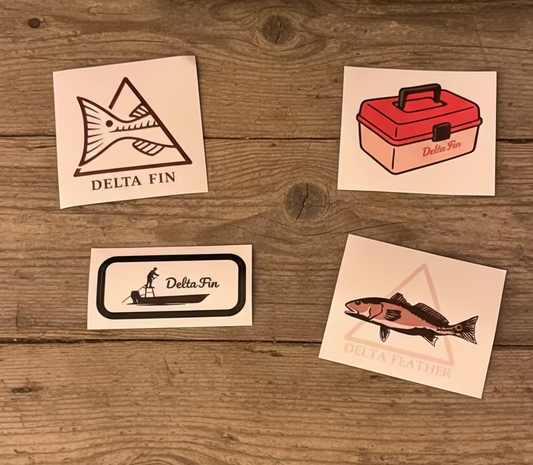 Four Delta Fin branded stickers on a wooden surface