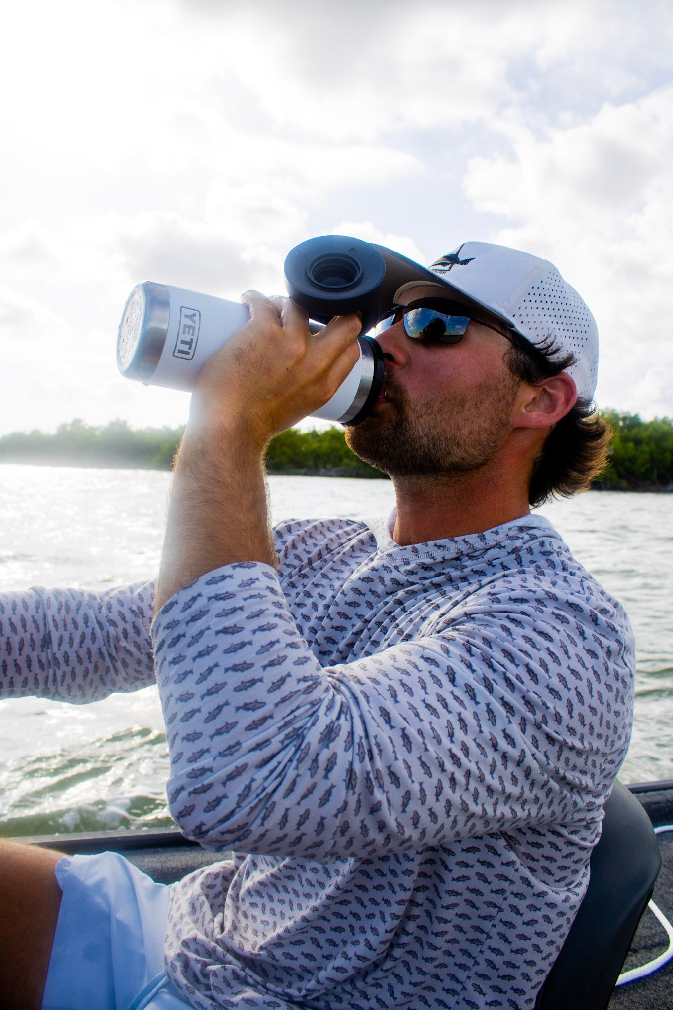 Redfish pattern hoodie being worn on a boat 