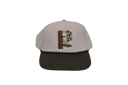 A lock on stand with a bow on a cream hat with a green bill. The letters DF are carved into the tree