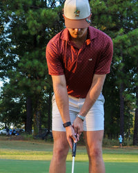Golfer in the Duck Hook hat standing over a putt on the green
